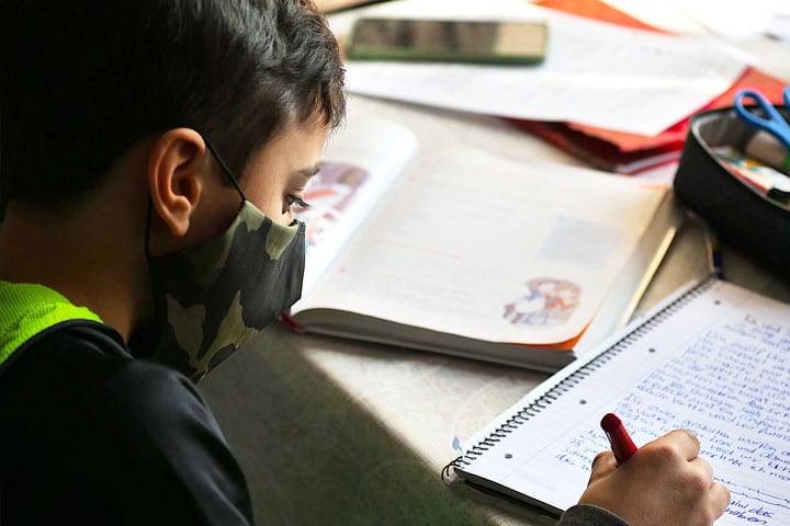 Student Writing with Mask on