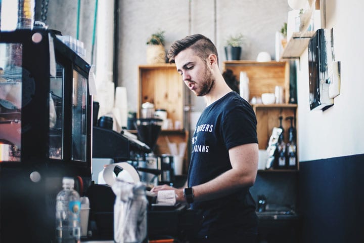 A young man works behind the counter in a coffee shop.