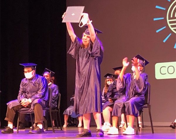 ACSSSD staff members assist a graduate on stage during the commencement ceremony.