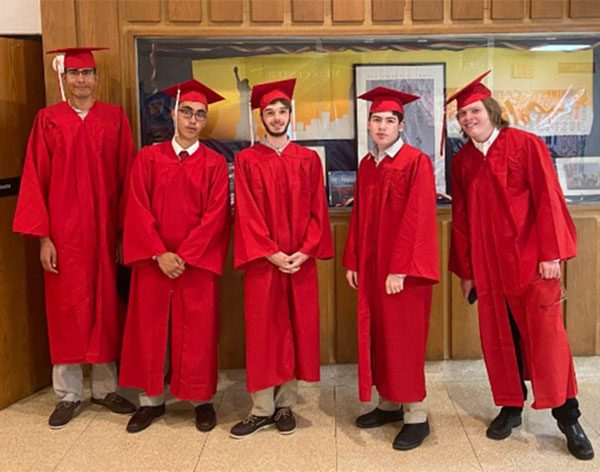 Members of the BCSSSD’s Evergreen Program Class of 2021 gather together in a hallway prior to the graduation ceremony, wearing traditional caps and gowns.