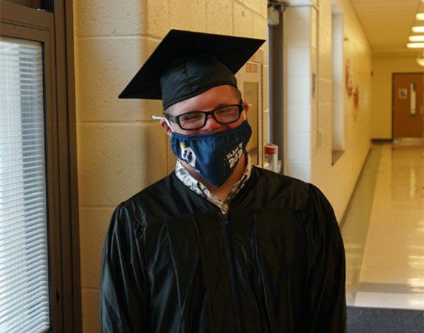 A proud GCSSSD graduate smiles behind his facemask in a hallway following the graduation ceremony.