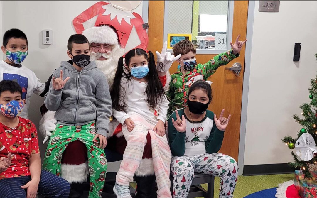 Bergen County Special Services School District students at the Union Street School who are deaf and hard of hearing pose with Santa while signing "I love you" and smile."