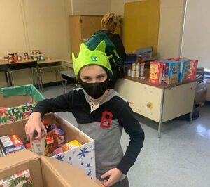 A Burlington County Special Services School District student wearing an elf hat loads a box up with food collected by the school to be distributed to those in need.