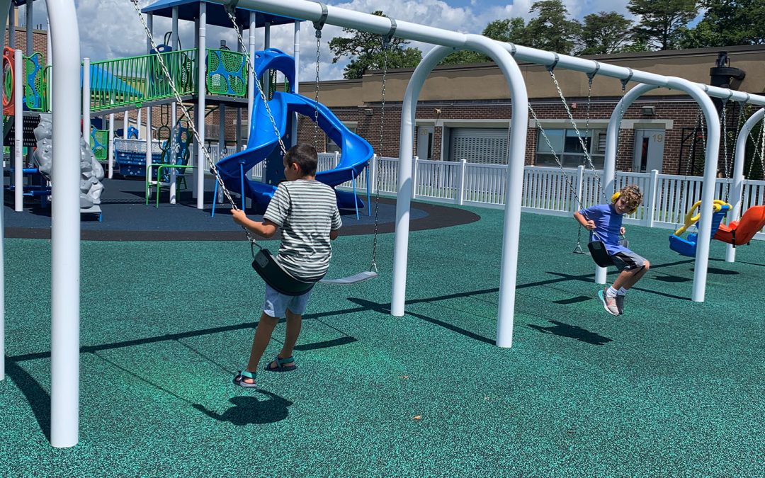 Two Children Swinging on New Playground