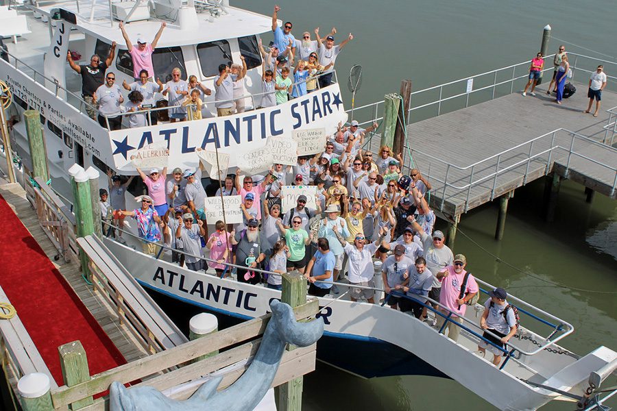 A fishing boat is docked and a group of people is cheering with their arms outstretched.