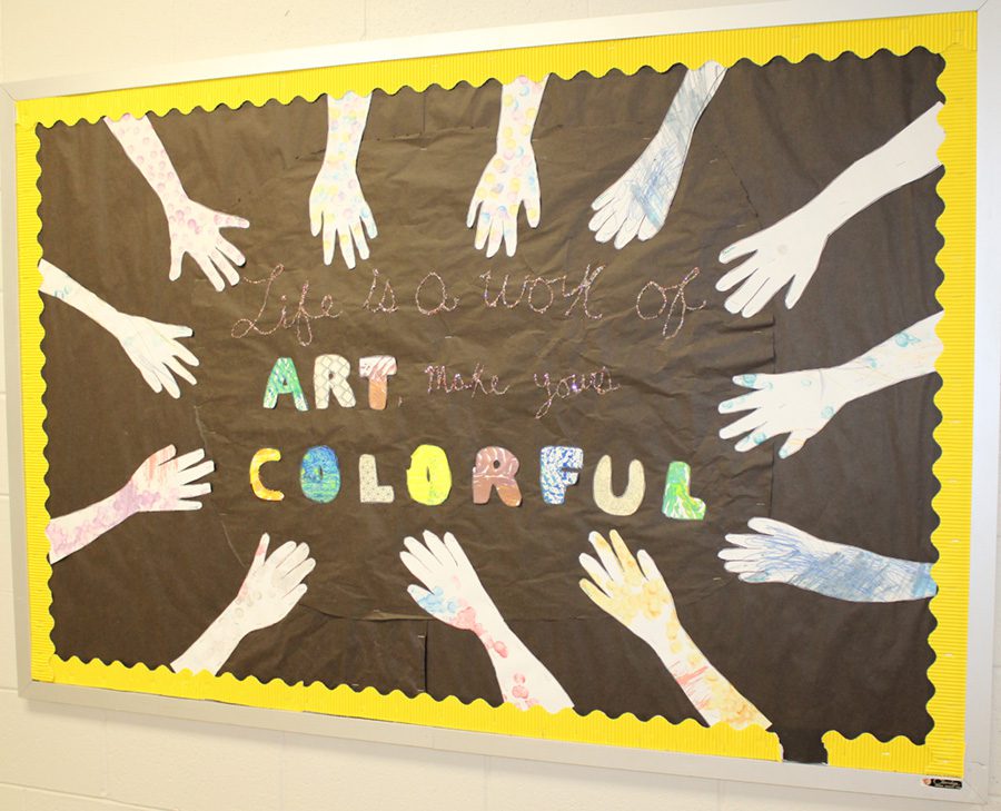 A bulletin board shows traced hands around the border and the middle says “Life is a work art, make yours colorful.”