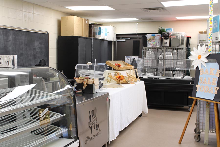 A bakery storefront with cases, displays and a Bake Sale Today sign is incorporated into a culinary classroom.